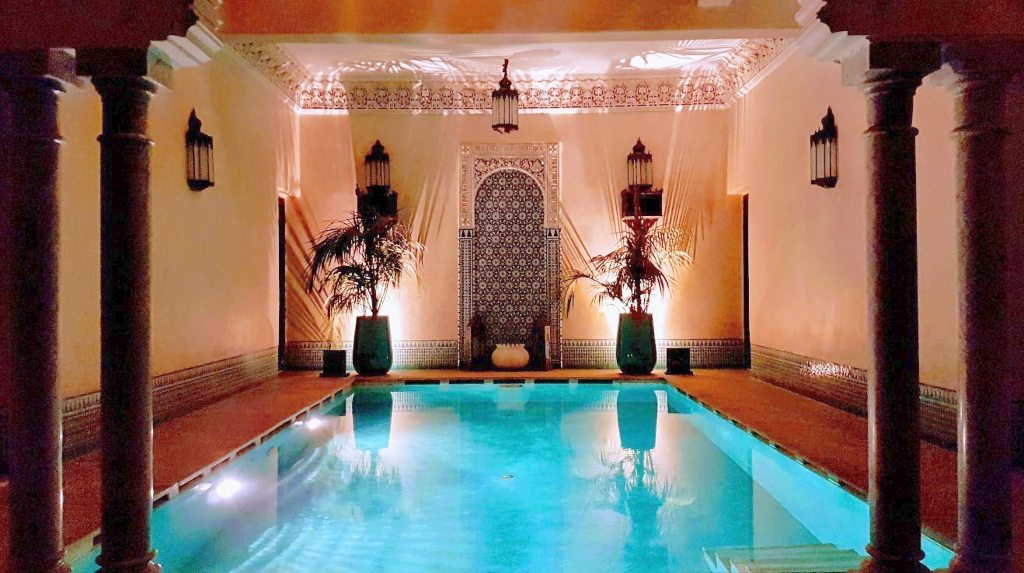Piscina iluminada en Riad Kniza, uno de los mejores riads en Marrakech para una estancia relajante.