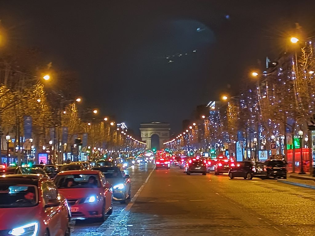 Campos Elíseos iluminados con el Arco del Triunfo al fondo, paseo nocturno por París.