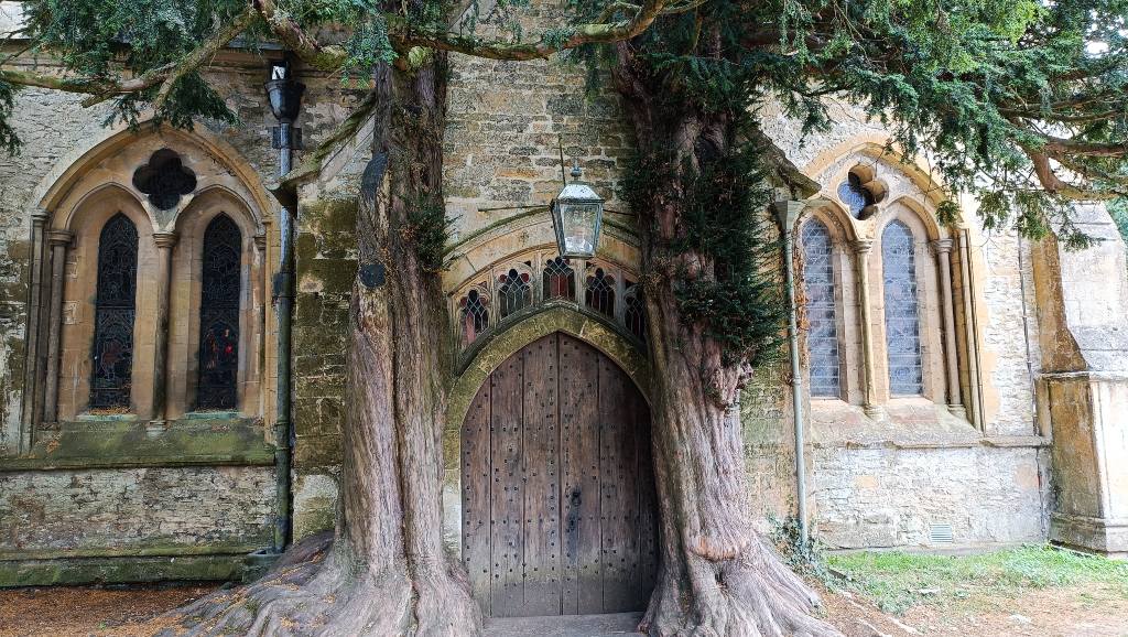 Iglesia de Stow-on-the-Wold con su puerta rodeada de árboles centenarios.