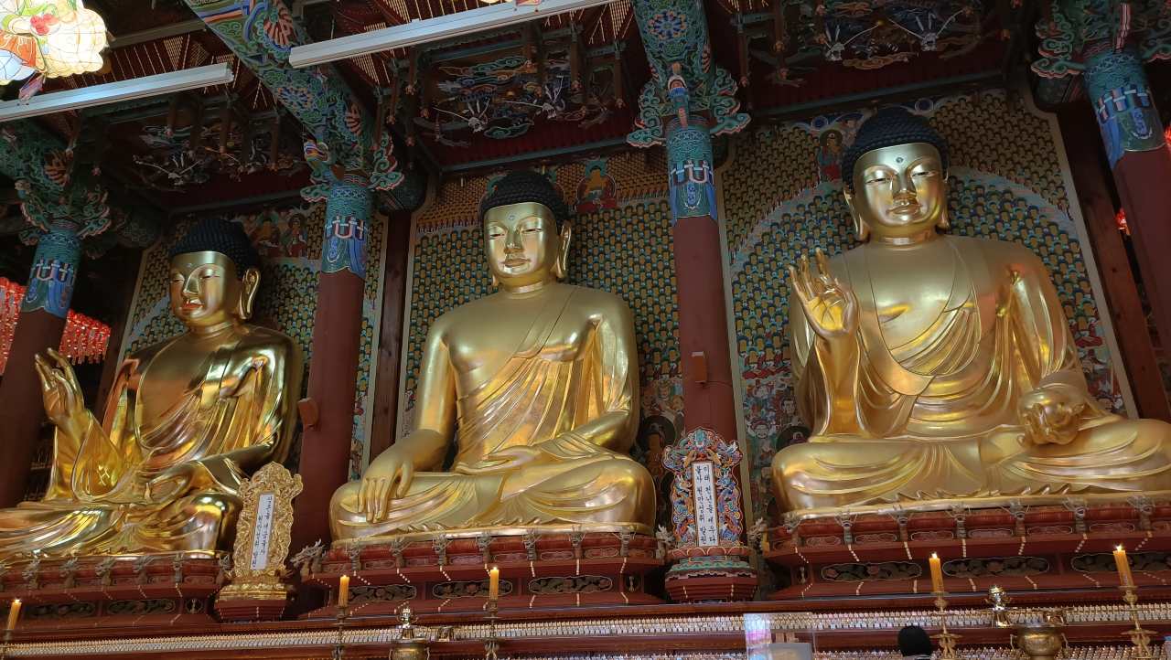 Tres grandes estatuas doradas de Buda en el salón principal del templo Jogyesa.