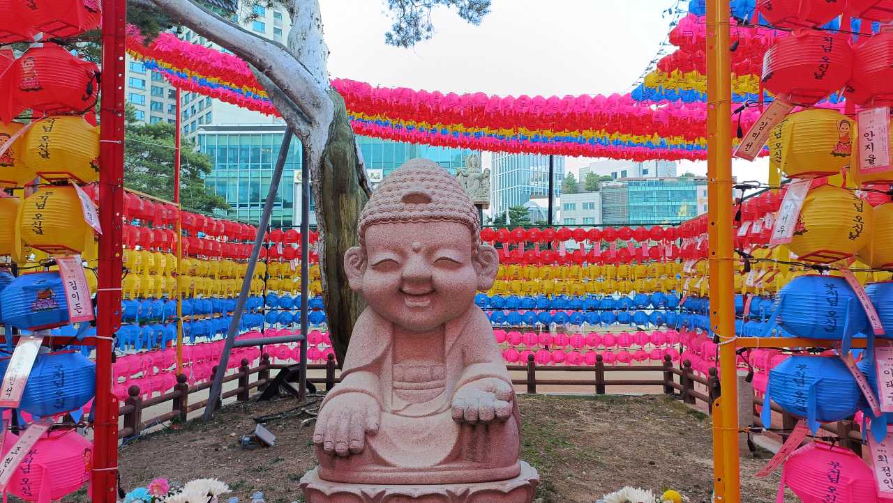 Estatua de Buda rodeada de farolillos de colores en el templo Jogyesa.